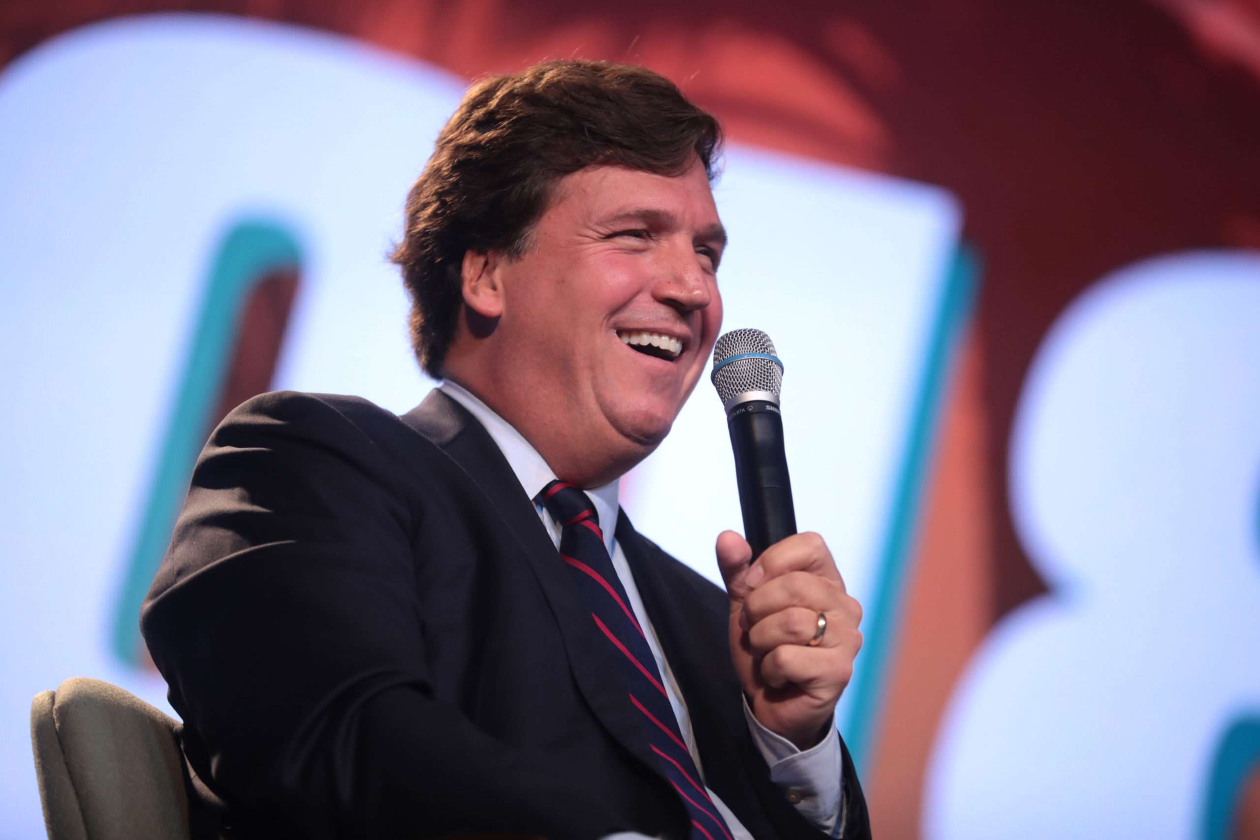 Political Americans Tucker Carlson talking into microphone at conference